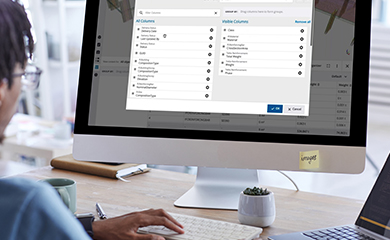A person works at a desk with a monitor displaying a Trimble software interface, featuring a column management dialog for BIM data.