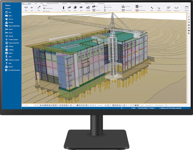 Computer monitor showing a detailed 3D building model and tower crane in the Trimble Tekla Structures BIM software interface.