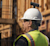 Construction worker with high-vis yellow vest and PPE wearing a hard hat with an Insta360 Camera attached on top via a mount.