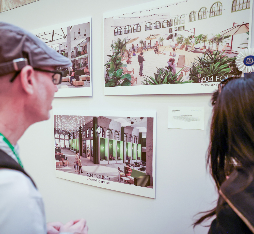 Two people viewing architectural renderings of the "404 FOUND" coworking space at the SketchUp Ascent competition exhibit.