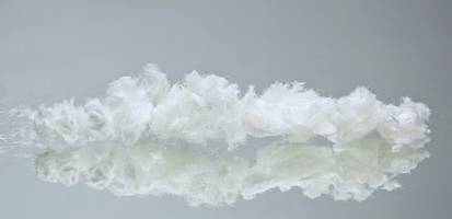 A delicate white cloud formation is reflected on a smooth, gray surface, creating a serene and tranquil atmosphere.