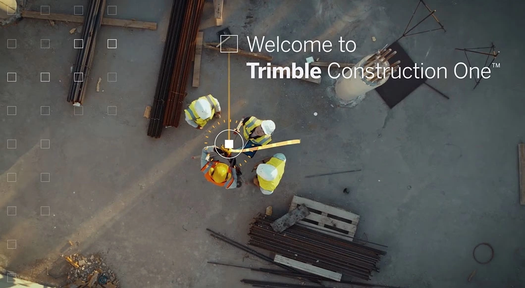Aerial view of construction workers on a site with "Welcome to Trimble Construction One" text and digital UI overlays.