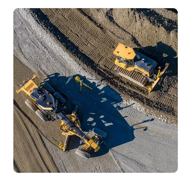 Aerial view of a motor grader and bulldozer using the Trimble Earthworks Grade Control Platform for grading on a dirt construction site.