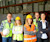 A group of five people standing in a warehouse setting.