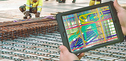 A person uses Trimble Connect AR on a tablet to overlay a 3D BIM model onto a construction site's rebar foundation.