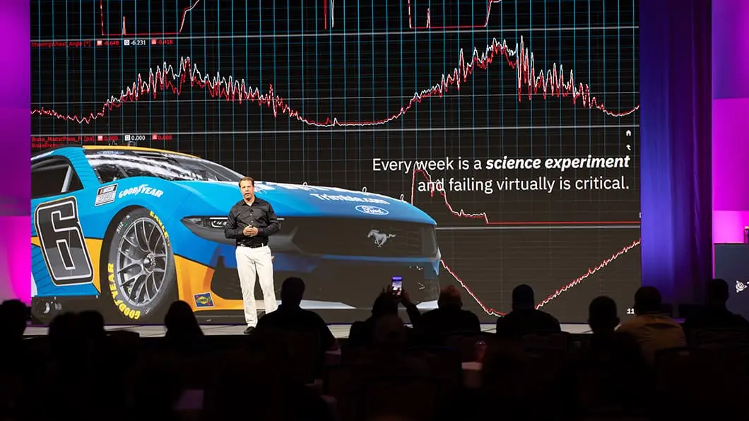 Brad Keselowski presents at Trimble Dimensions before a screen showing his No. 6 Ford Mustang and text about failing virtually.