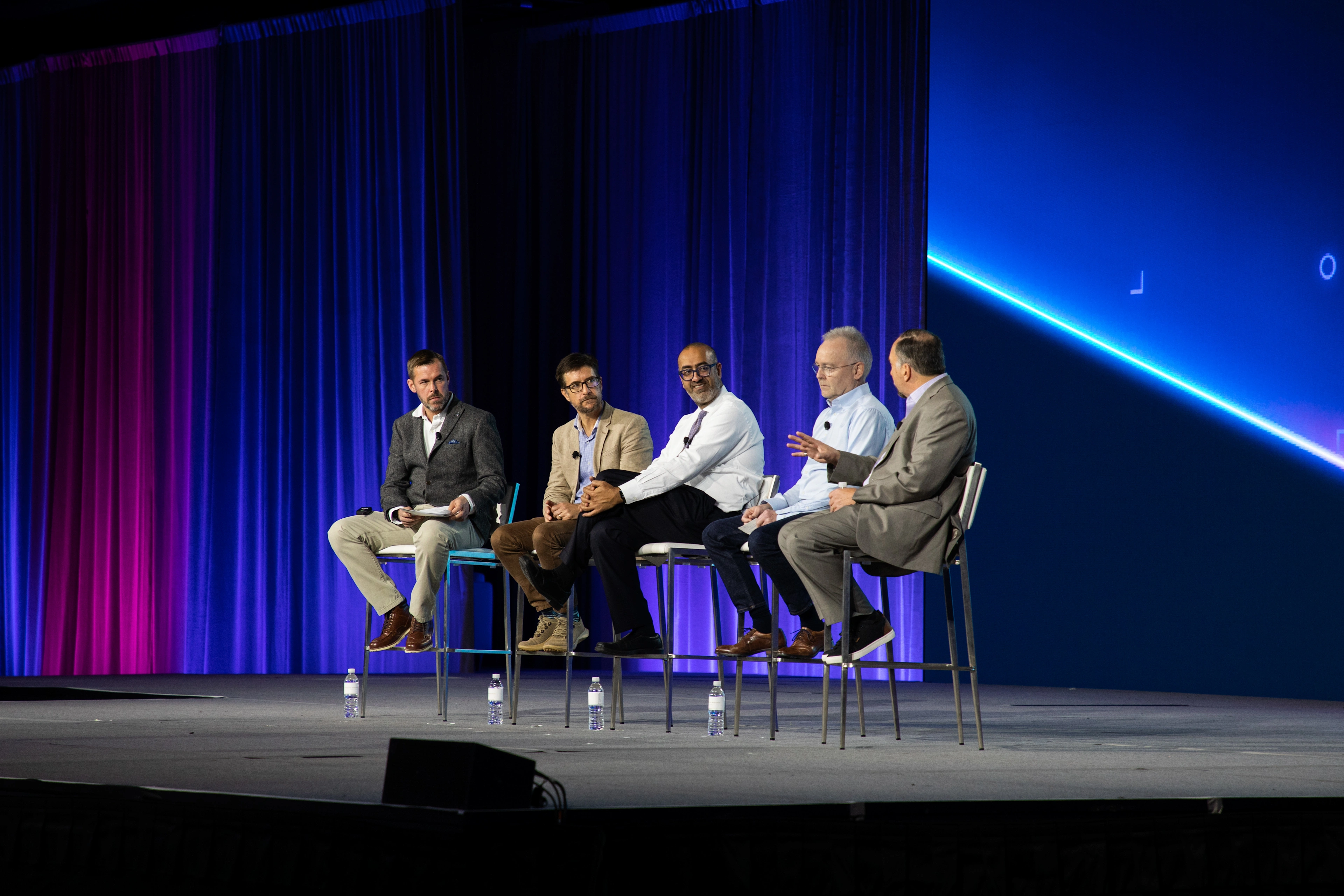 Trimble executives, including Aviad Almagor and Peter Large, participate in a panel discussion on a stage at the Trimble Dimensions conference.