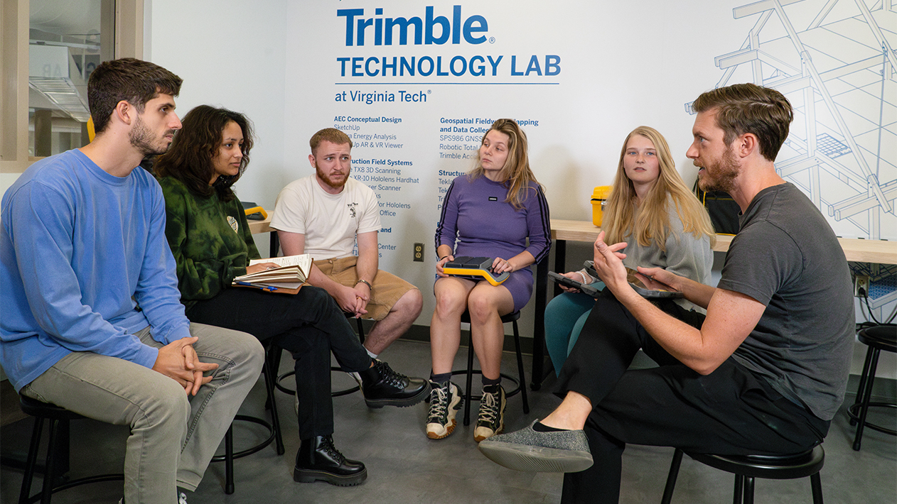 Students & professors talking while holding Trimble geospatial equipment at Trimble Technology Lab at Virginia Tech