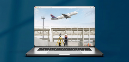 Construction person using Trimble Geospatial equipment at airport site with plane flying above