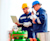 Two male workers in protective gear are standing outdoors, seemingly at an industrial site.
