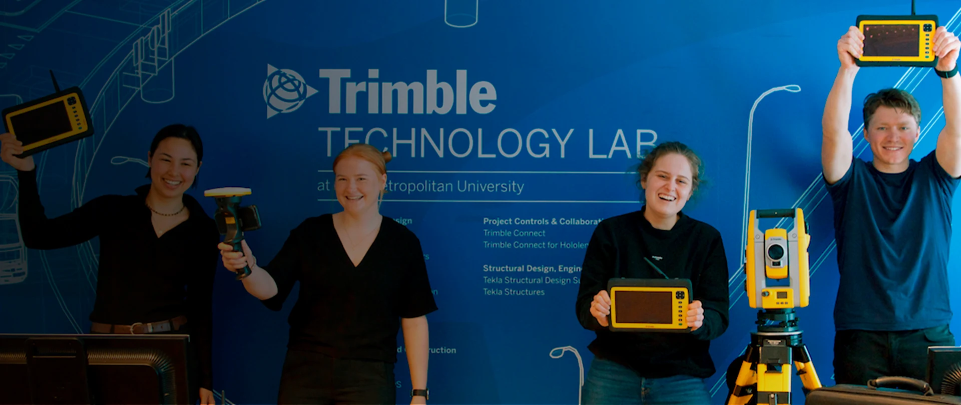 Tevreden studenten in het Trimble Technology Lab met Trimble Geospatiale apparatuur die glimlachend naar de camera kijkt
