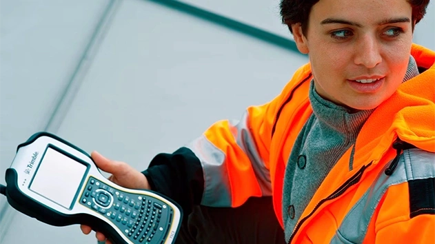Woman in reflective vest using Trimble TSC3 equipment