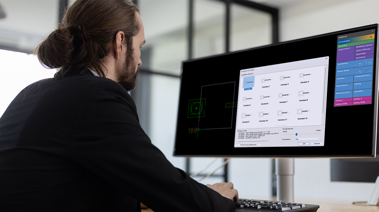 MEP engineer at desk viewing Stabicad for IntelliCAD on a monitor.