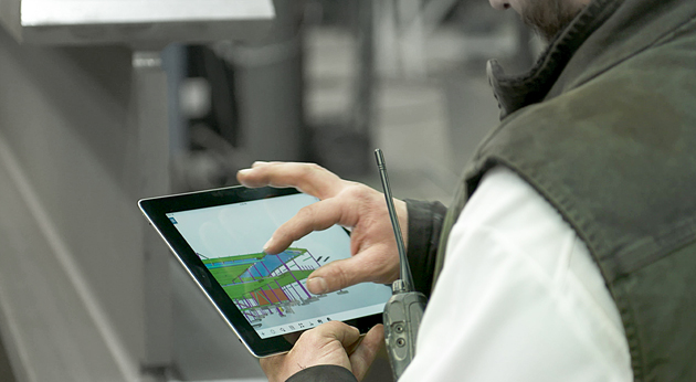 A construction professional uses a Trimble tablet with FieldLink software to view a 3D structural BIM model on a job site.