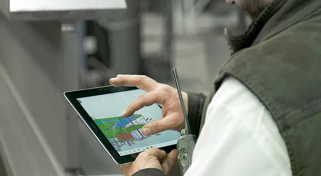 A construction professional uses a Trimble tablet with FieldLink software to view a 3D structural BIM model on a job site.