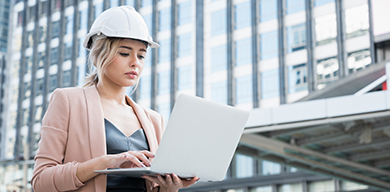 A women viewing a monitor displaying Trimble WorksOS software, featuring a site map and job site production targets dashboard.