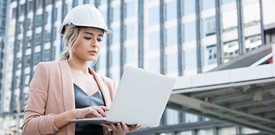 A women viewing a monitor displaying Trimble WorksOS software, featuring a site map and job site production targets dashboard.