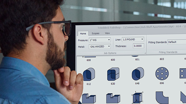 A man wearing glasses looks at a computer screen showing 2D and 3D parts within a Trimble FabShop software.