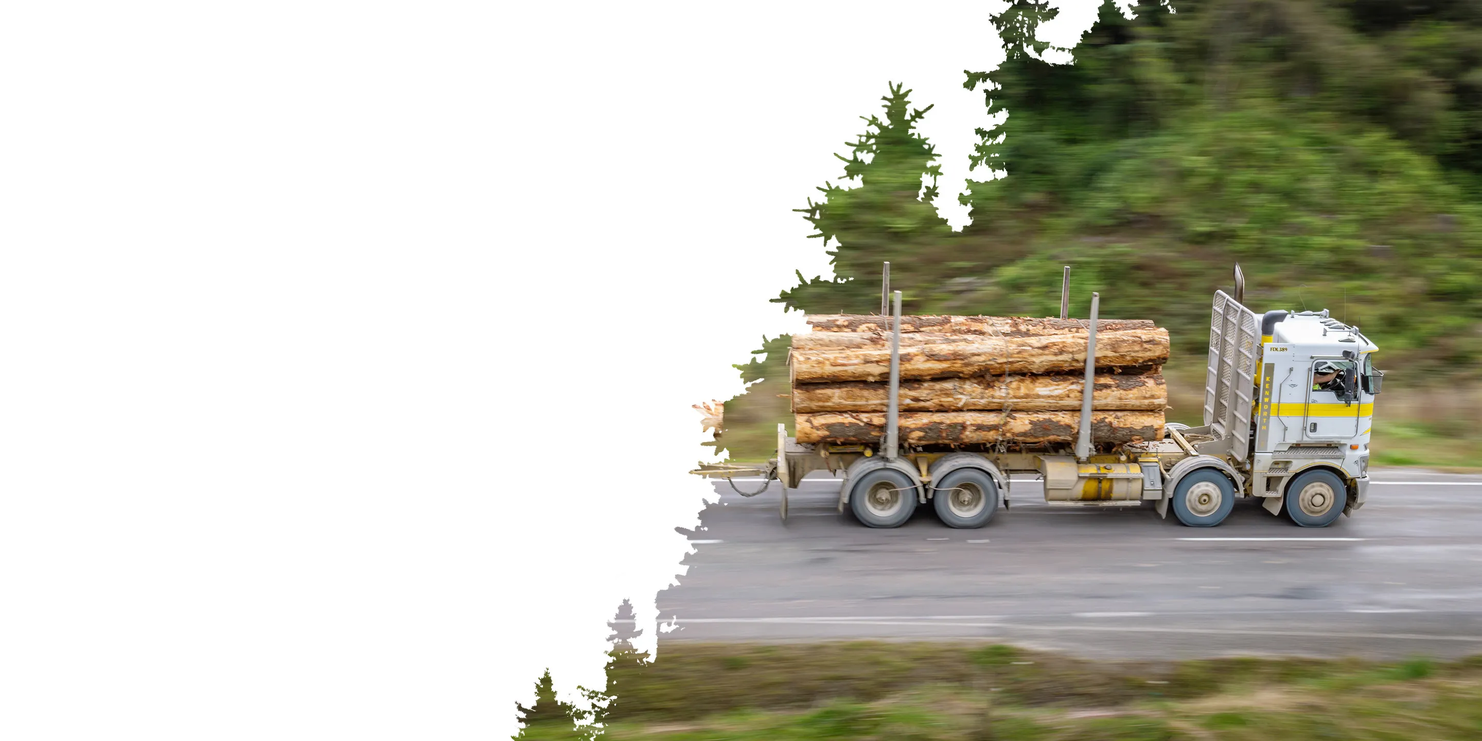 A logging truck carrying large timber logs moves along a highway surrounded by green foliage. The motion blur emphasizes speed and activity.