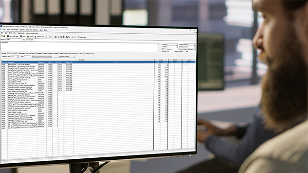 A bearded man in an office views "Enterprise Contract Costing" software on a monitor.