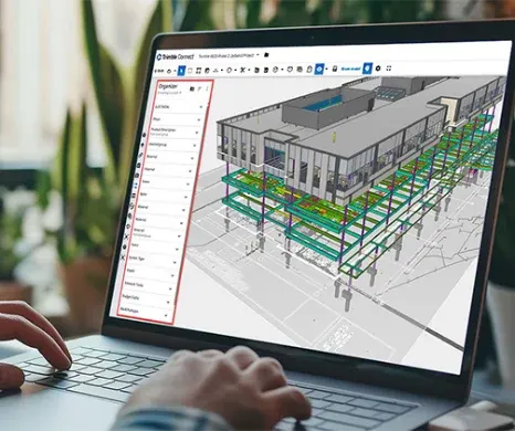 Iemand bekijkt een 3D-gebouwmodel in Trimble Connect op een laptop; de Organizer-zijbalk is rood omkaderd.