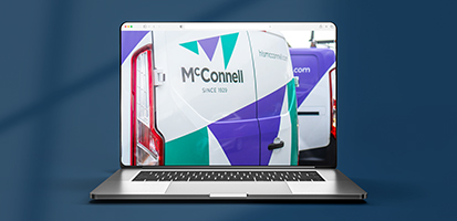 Laptop screen displaying a McConnell construction case study featuring company service vans with brand logos.