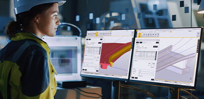 A female engineer in a hard hat uses Trimble Tekla Structures on dual monitors to analyze 3D BIM models of structural components.