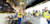 An instructor at the Trimble Dimensions offsite points to a large screen while speaking to a group of focused attendees in PPE