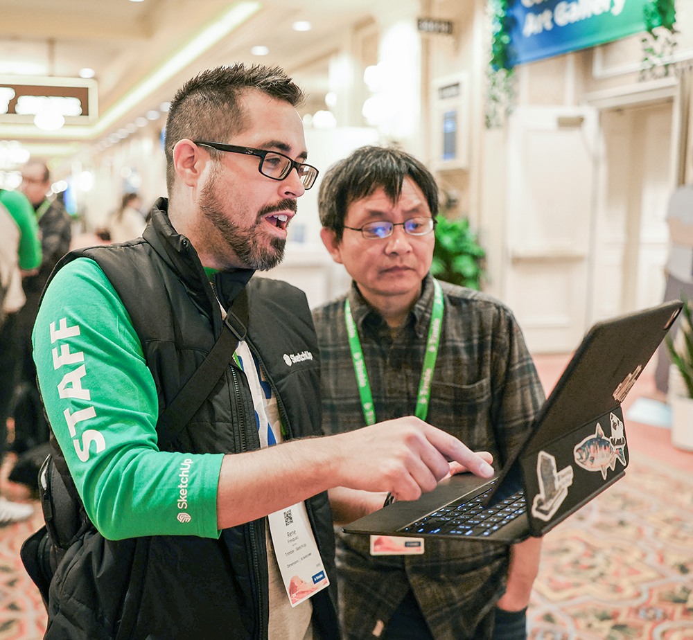 A group of professional attendees discussing a digital display and sharing ideas at the Trimble Dimensions conference.