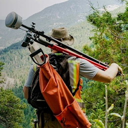 Man holding Trimble Geospatial equipment looking at trees on mountains