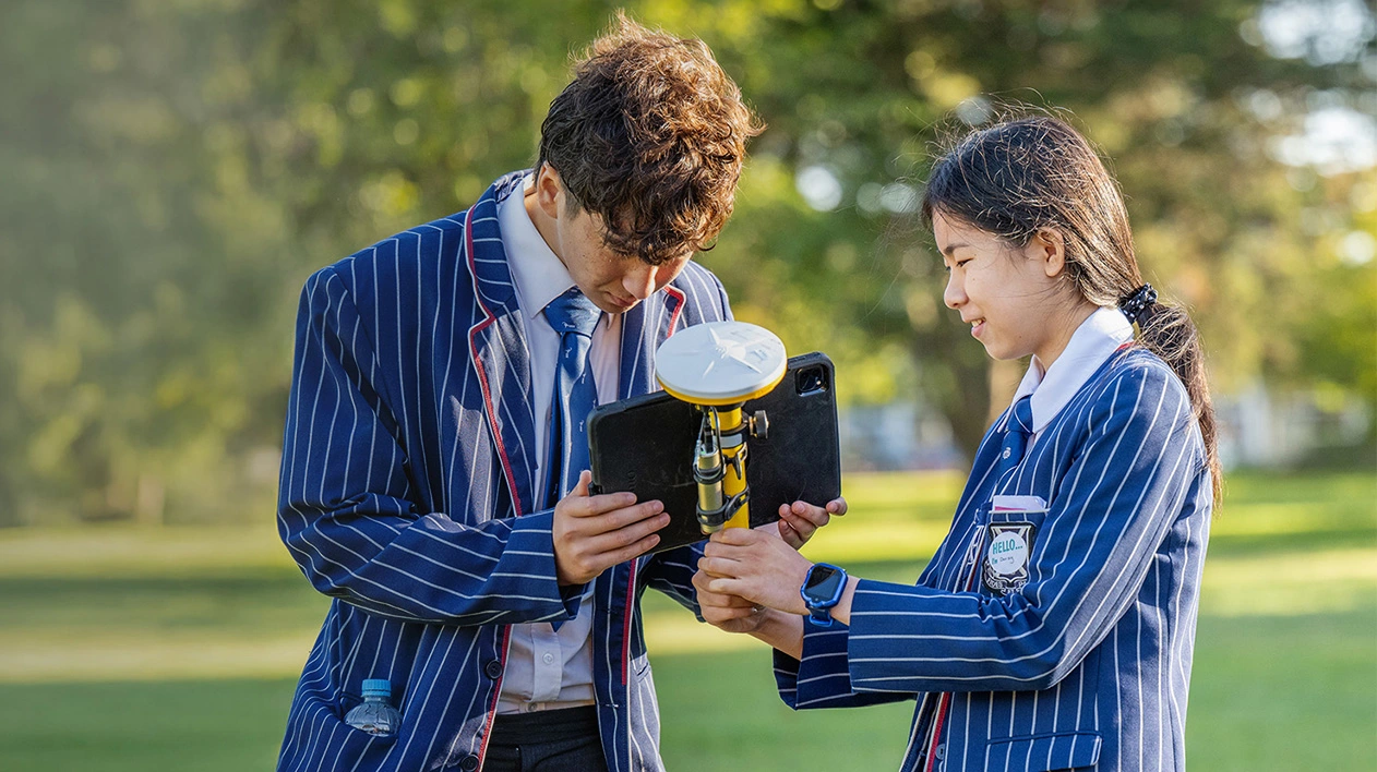 Two students in striped blazers using Trimble SiteVision outdoors during a career day in Christchurch, NZ