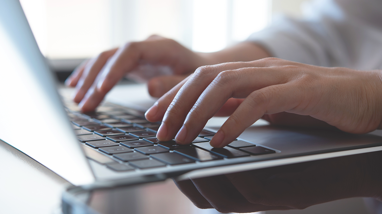 Hands typing on laptop