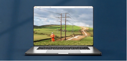 Construction worker looking at overhead power towers in a field