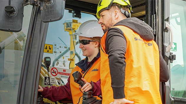 People in hard hats and Trimble vests operating heavy machinery