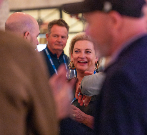 A smiling Cyndee Hoagland, Trimble SVP, networks at a corporate event with attendees wearing blue branded lanyards.
