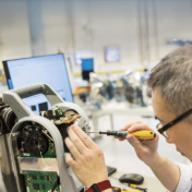A technician performs precision repairs on electronic equipment in a professional service center.