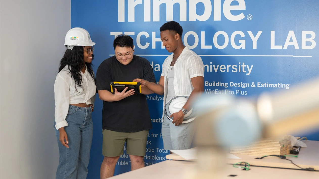 Three students at Florida A&M Trimble Technology Lab talking while looking at tablet