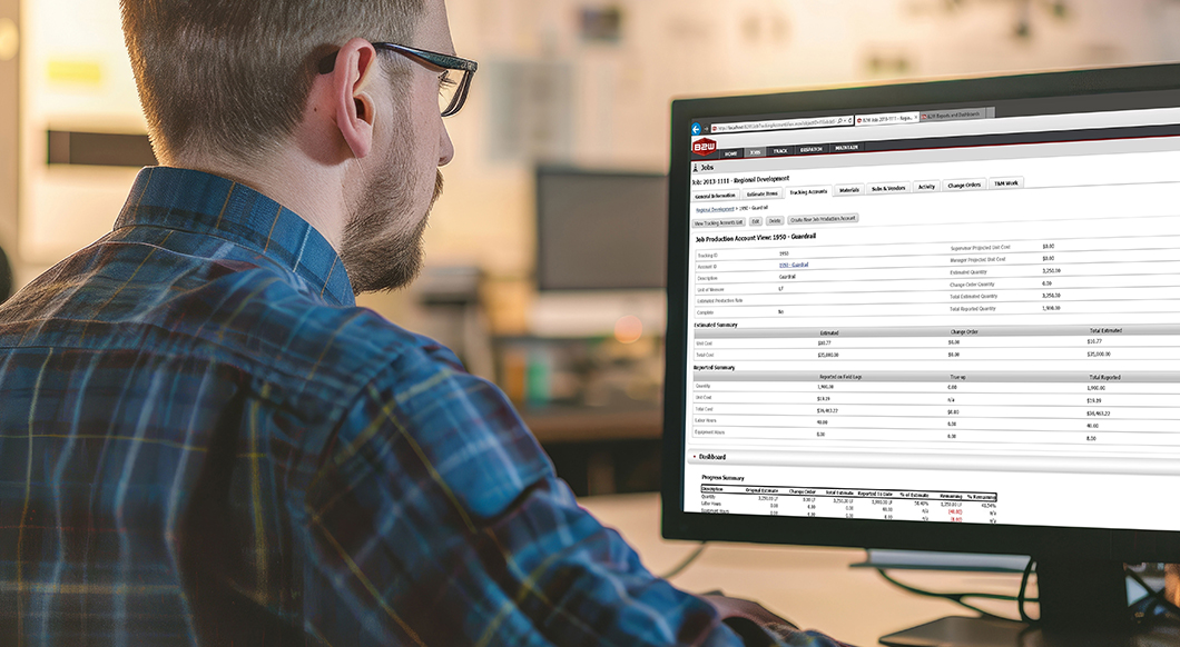 A man views B2W construction software by Trimble on a computer monitor, showing project estimates and progress tracking data.