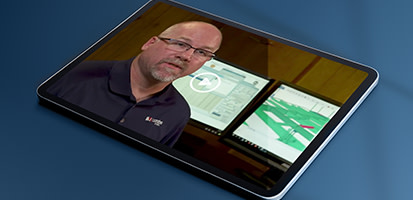 A tablet displays a video of a man presenting Trimble Tekla Structures software. A 3D structural model with green beams is visible in the background.