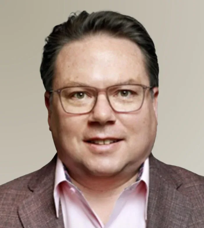 Tim Long from Snowflake, wearing a pink collared shirt with a subtle patterned interior and a brown patterned blazer, against a plain background.