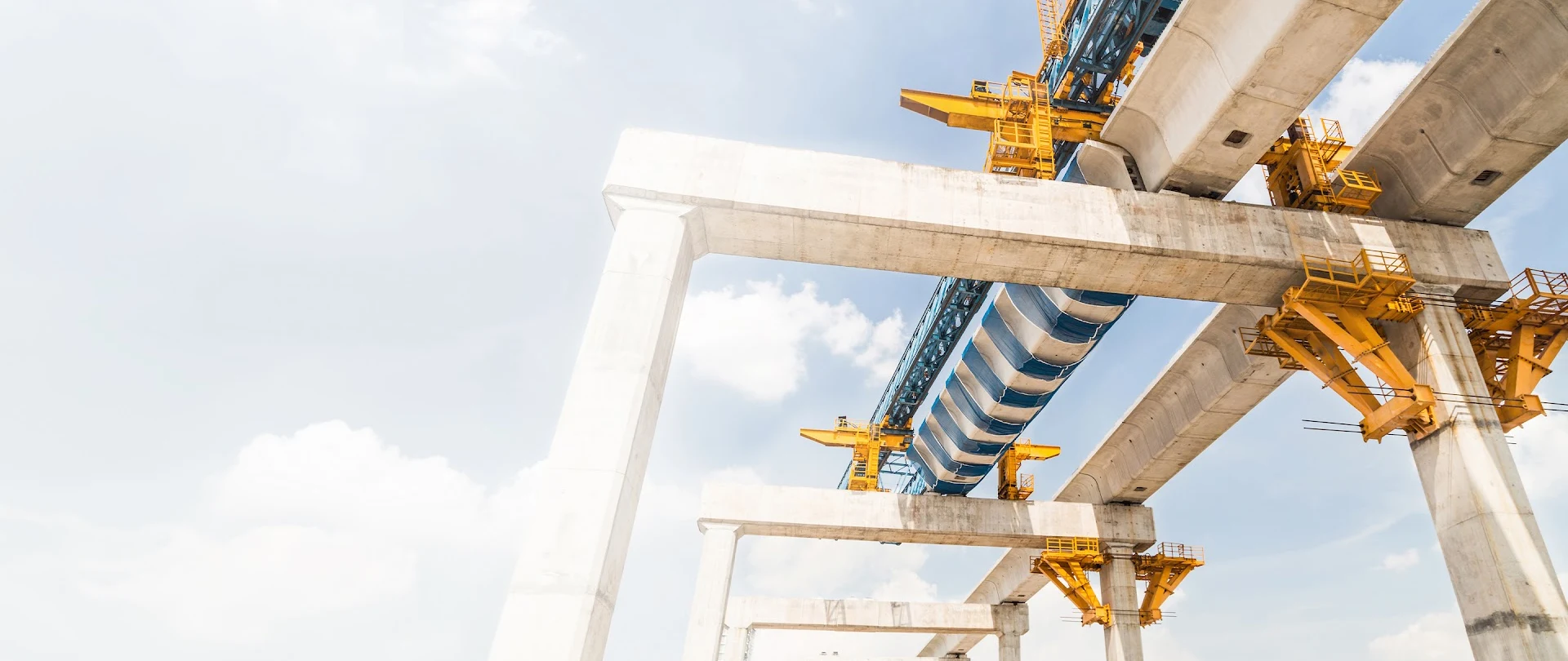 A launching gantry installs concrete beams for an elevated bridge, illustrating civil infrastructure work for Trimble Construction One.
