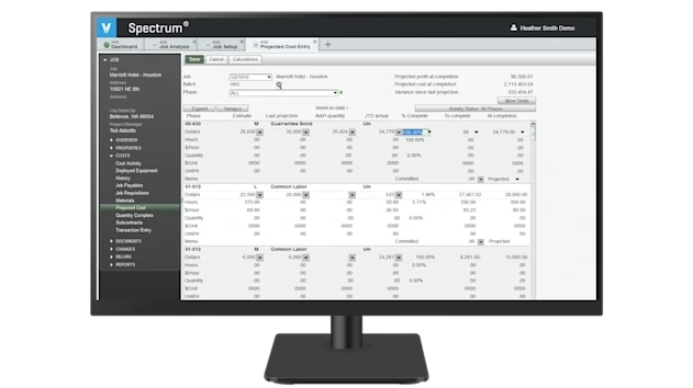 A desktop monitor displays Viewpoint Spectrum construction ERP software
