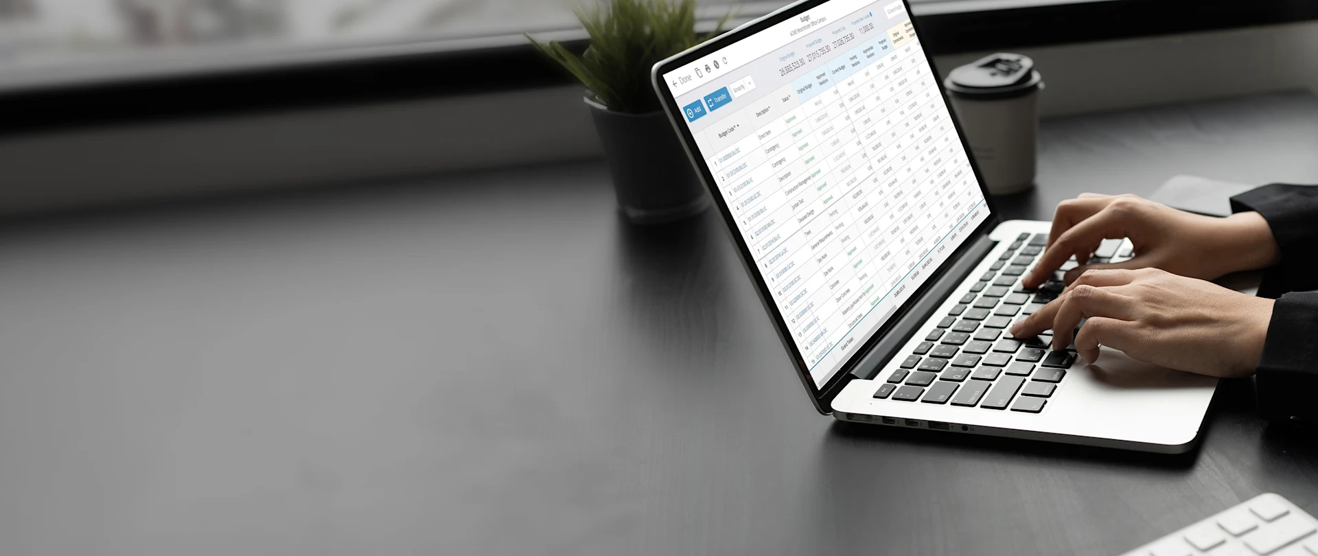 A person uses Trimble ProjectSight software on a laptop to manage the ACME Westminster Office Campus construction budget.