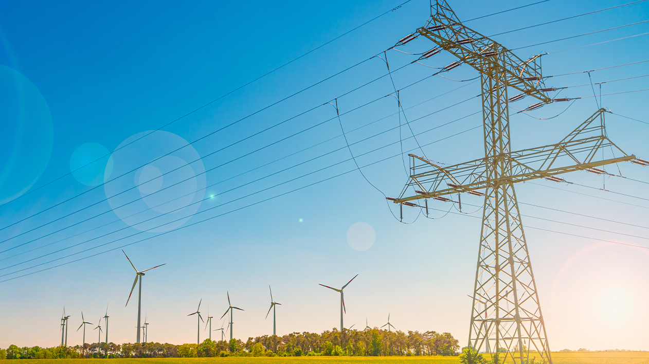 A bright, wide-angle shot of a tall electrical transmission tower with numerous power lines stretching across a field.