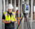 Person with reflective vest and hard hat using Trimble X9 Geospatial equipment to create a 3d scan on jobsite