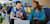 Two young professionals talking in casual setting while using laptop