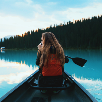 Une personne qui rame un canoé sur une eau bleue entourée de montagnes