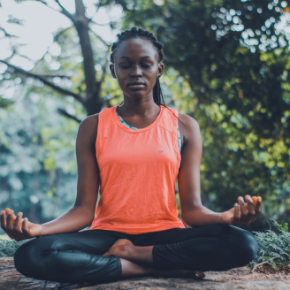 A person with dark brown skin is doing yoga outside