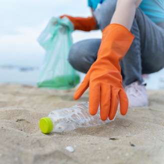 Une personne qui ramasse une bouteille de plastique sur la plage
