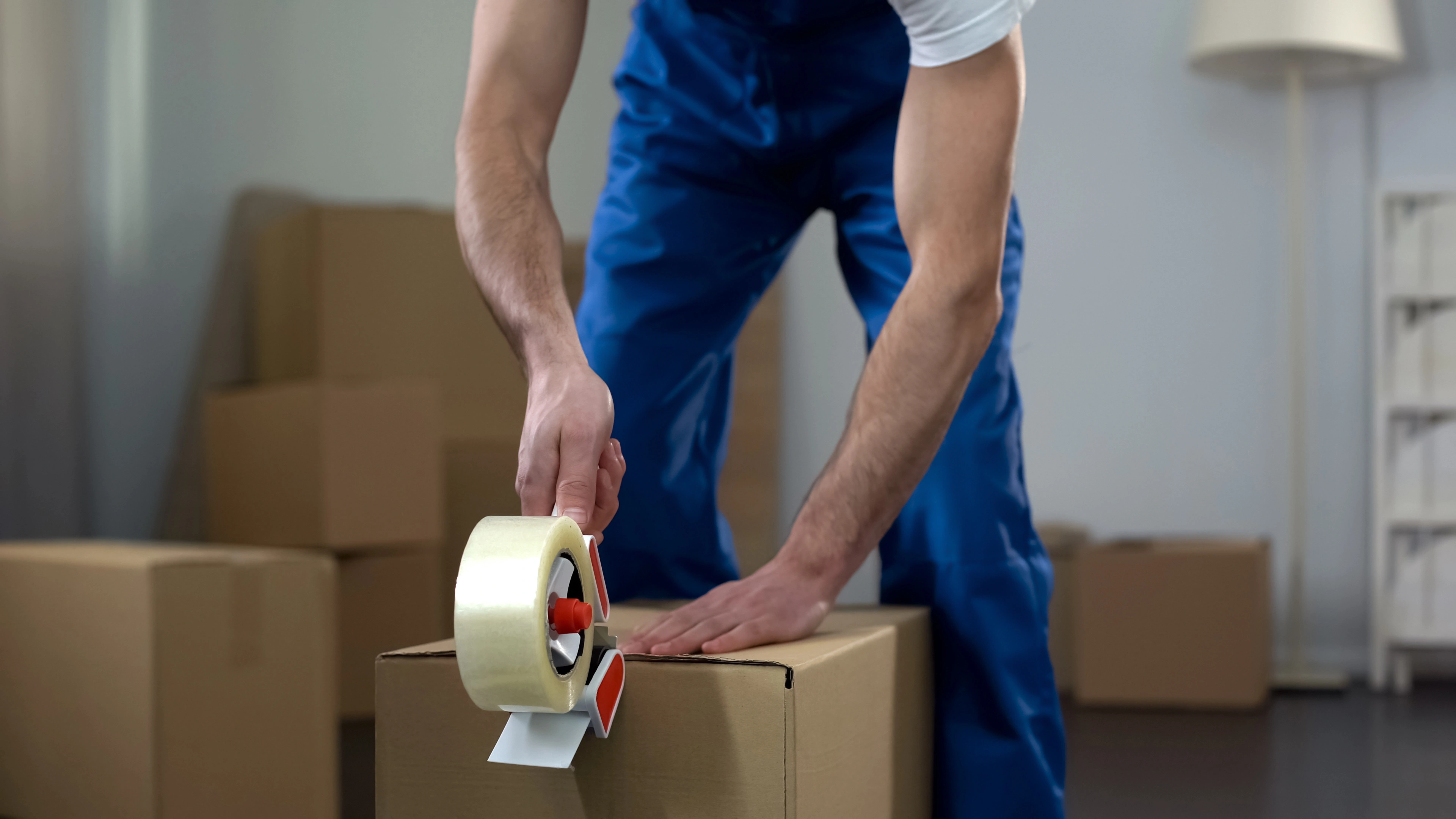 photo of a man taping a box for moving house
